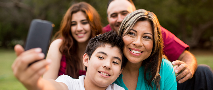 Adolescent sitting with his family as they all pose for a selfie 