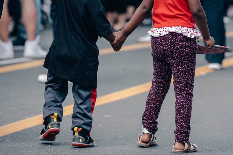 Two kids crossing the street, holding hands