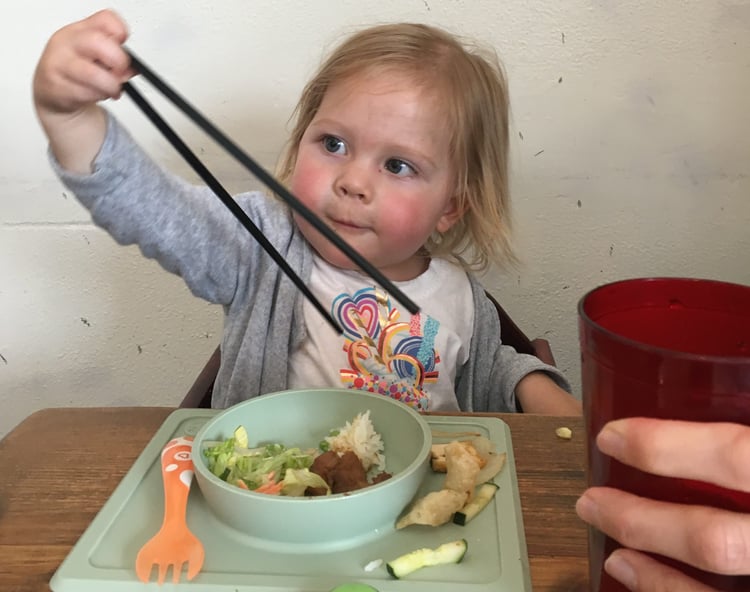 little girl using chopsticks